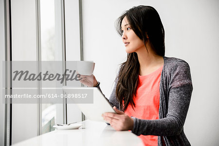 Woman with digital tablet during break looking out window