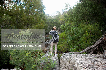 Teenage hiker taking photographs from rocks
