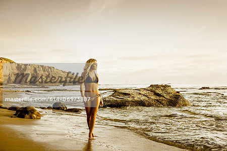 Young woman in bikini walking along beach