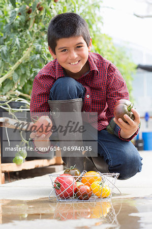 Boy crouching holding ripe tomatoes