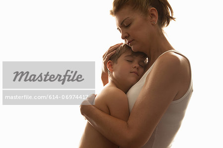 Boy hugging his mother around the waist stock photo - OFFSET