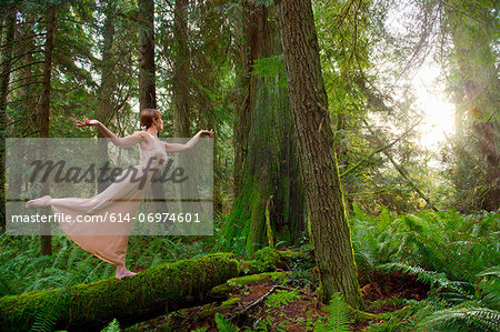 Mature woman standing on log in forest