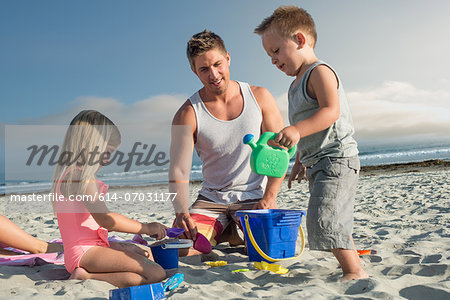 Young man playing with son and daughter on beach