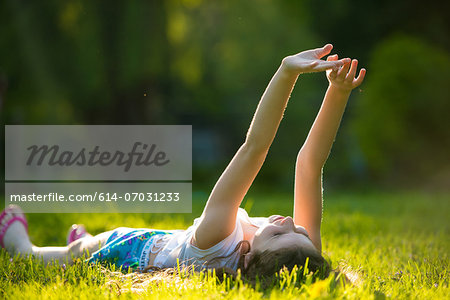 Girl lying on grass with arms raised