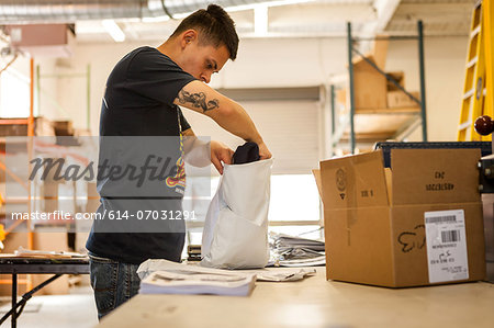 Worker packing garment in screen print workshop