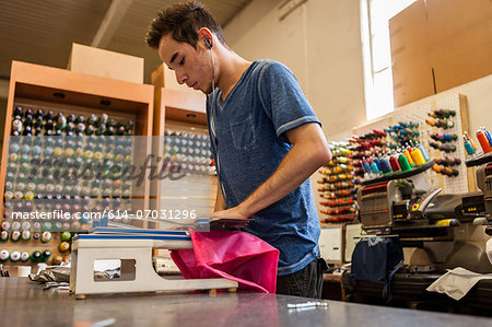 Worker using embroidery machine in t-shirt  printing workshop