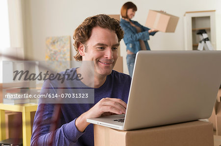 Mature man using computer whilst moving house