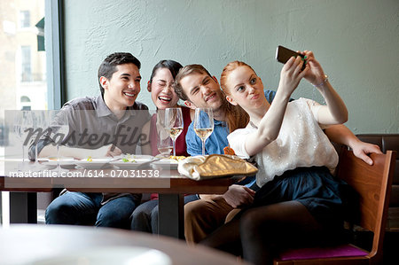 Four friends photographing themselves in restaurant