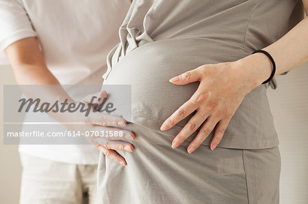 Man touching pregnant woman's stomach, cropped portrait