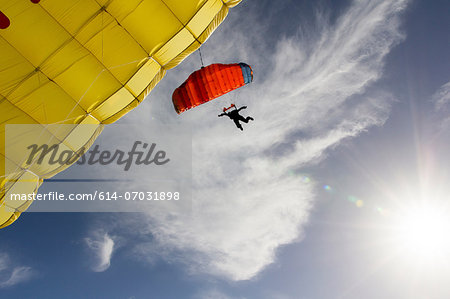 Female skydiver steering yellow parachute