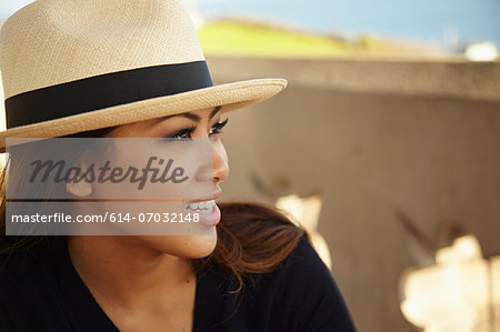 Portrait of smiling young woman wearing sunhat at coast