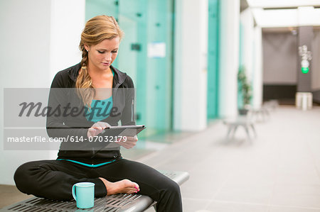 Young woman in gym corridor using digital tablet