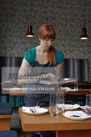 Mid adult woman preparing table in restaurant