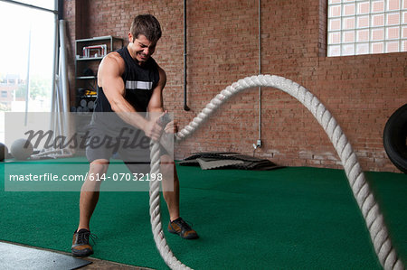 Male bodybuilder using ropes in gym