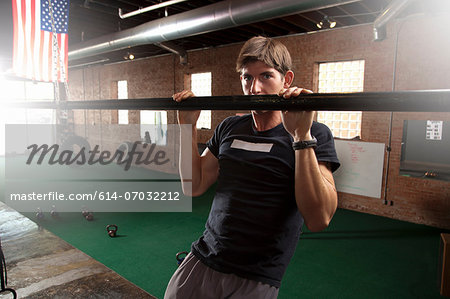 Bodybuilder pulling up on bar in gym