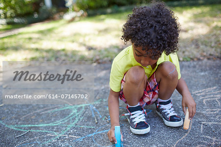 Boy drawing with chalk on sidewalk