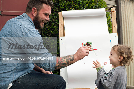 Father fooling around painting on daughter's face