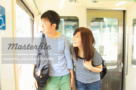 Young couple standing on train, looking through window
