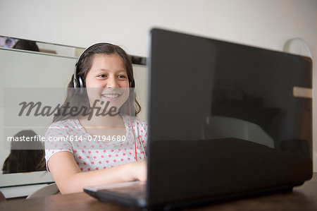 Teenage girl wearing headphones using laptop