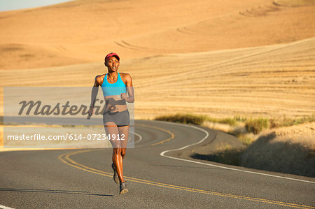 Young woman running on road, Bainbridge Island, Washington State, USA Young woman running on road, Bainbridge Island, Washington State, USA