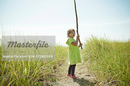 Portrait of female toddler holding long stick