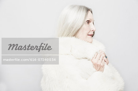 Studio portrait of senior woman in white fur coat