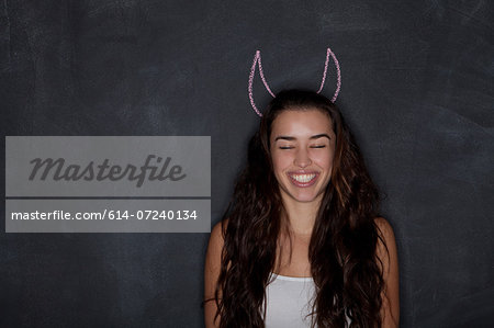 Young woman by blackboard with horns