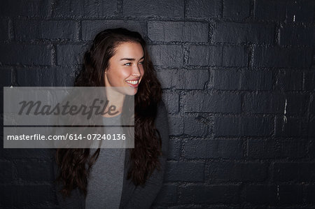 Young woman by black brick wall