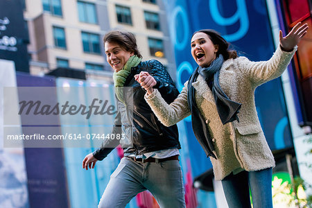 Young couple running on street, New York City, USA