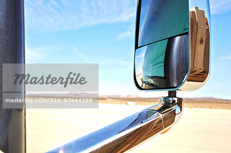 View of car wing mirror,  arid landscape and distant mountains