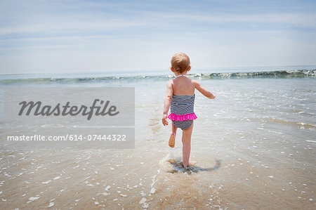 Female toddler running into the sea