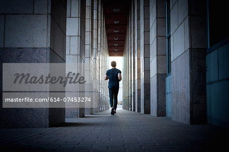 Young man running along urban sidewalk