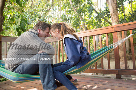 Father and daughter sitting on hammock