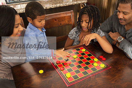 Mid adult couple and children playing draughts at dining table