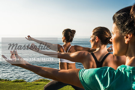 Women on cliff, practising yoga