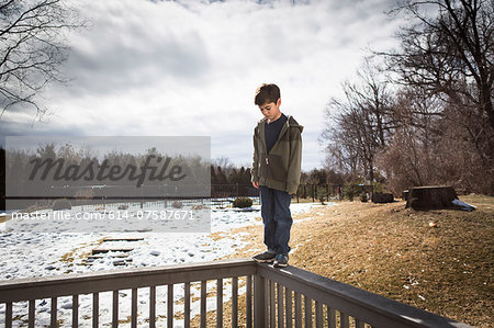 Boy balancing on top of fence in park