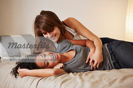 Affectionate young female couple relaxing on bed