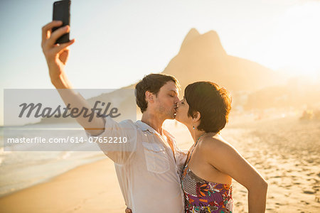 Young couple photographing themselves kissing, Ipanema Beach, Rio, Brazil