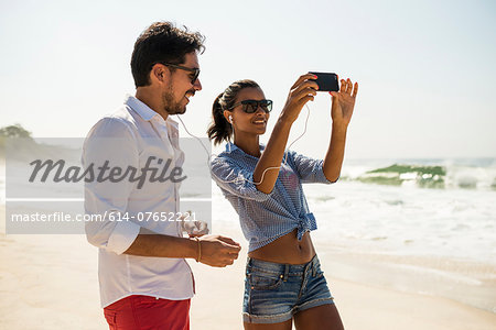 Couple sharing music from smartphone, Arpoador beach, Rio De Janeiro, Brazil
