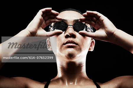 Young woman putting on swimming goggles