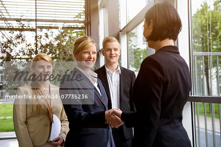 Business team greeting young female colleague