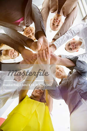 Worms eye view of seven business women and men in a circle holding hands in office Worms eye view of seven business women and men in a circle holding hands in office
