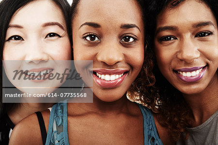 Close up studio portrait of three smiling young women