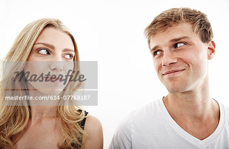 Studio portrait of young couple looking sideways at each other