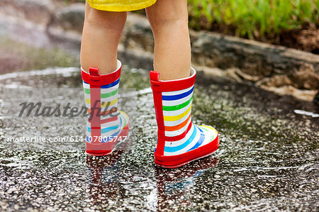 Legs of girl wearing rubber boots standing in rain puddle Legs of girl wearing rubber boots standing in rain puddle