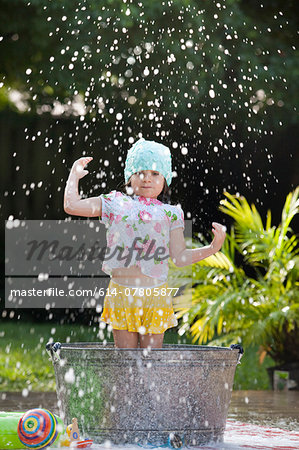 Girl standing in bubble bath in garden splashing soap bubbles