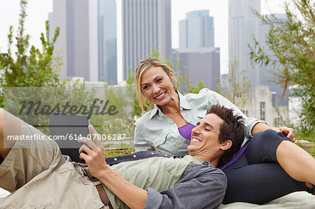 Couple relaxing in park by city