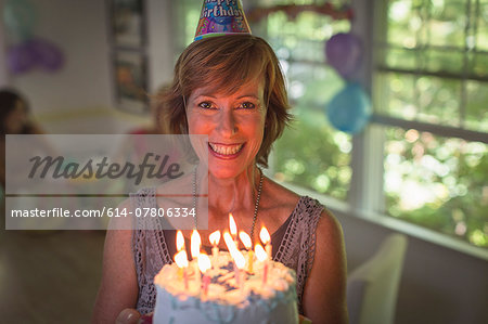 Portrait of mature woman holding birthday cake with candles
