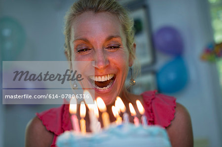 Mature woman holding birthday cake with candles