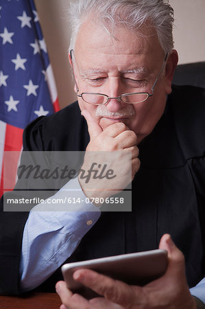 Senior judge reading digital tablet